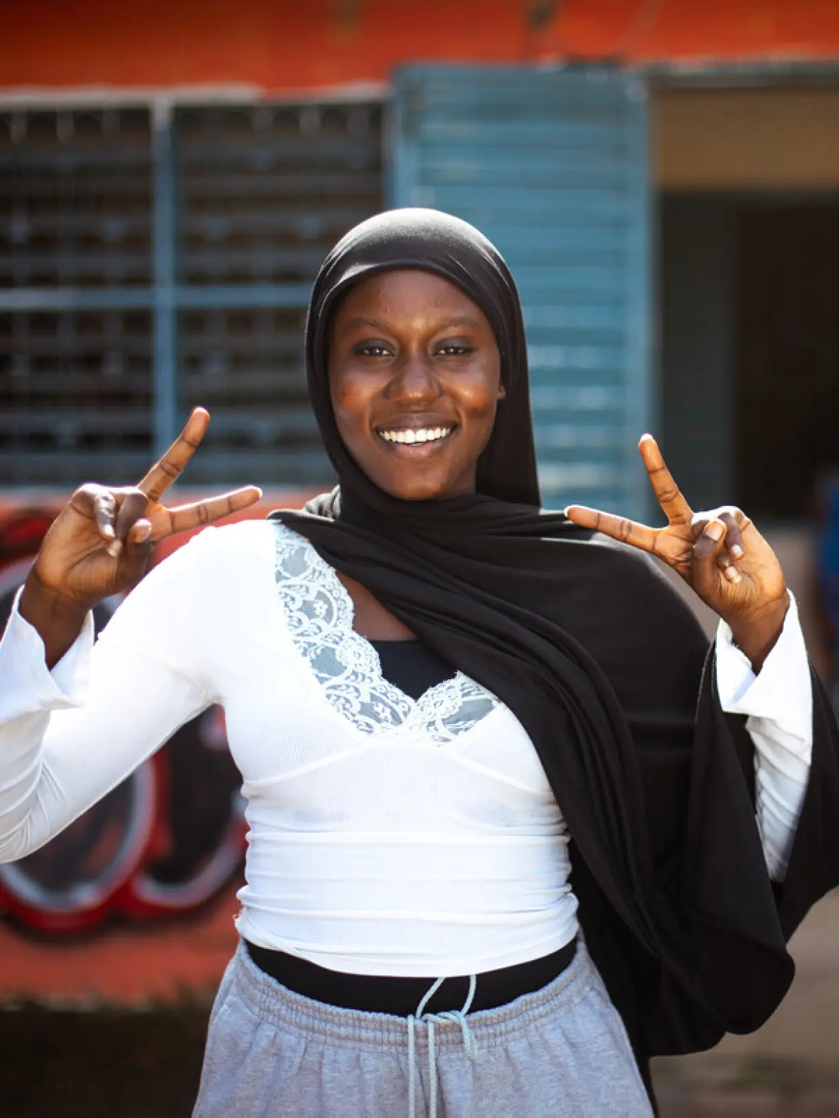 Coumba standing up doing two peace signs with both hands